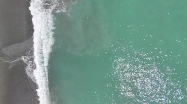 Okyanus dalgalarının sakin bir hareketle kumsala düşüşünün havadan görüntüsü. Seyahat kavramı
