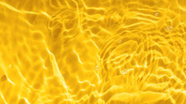 Güneş ışığı altında dalgalanan sarı suyun soyut arkaplanı. Üst manzara, düz yatış. İş için yaratıcı arka plan konsepti, kozmetik reklamcılığı. Boşluğu kopyala