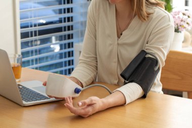 Beyaz bir kadın kan basıncını evde ölçüyor. Sağlık hizmeti kavramı