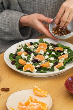 Portakallı, mavi peynirli ve cevizli taze ıspanak salatası hazırlayan kadın. Sağlıklı gıda kavramı