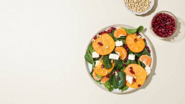 Taze hurma ve çam fıstıklı ıspanak salatası. Kış yemeği kavramı. Boşluğu kopyala