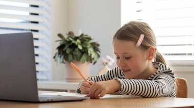 Evde çalışan, dizüstü bilgisayarın başında oturan bir çocuk. Çevrimiçi okulda okuyan tatlı bir kız. Eğitim ve e-öğrenim kavramı.