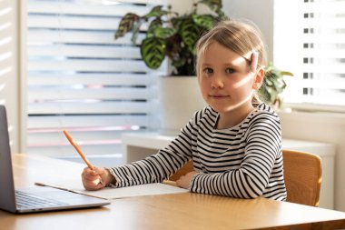 Evde çalışan, dizüstü bilgisayarın başında oturan bir çocuk. Çevrimiçi okulda okuyan tatlı bir kız. Eğitim ve e-öğrenim kavramı.