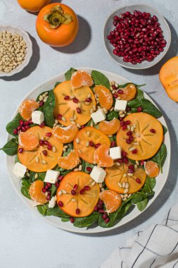 Taze hurma ve çam fıstıklı ıspanak salatası. Kış yemeği kavramı.
