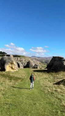 Çocuk açık mavi gökyüzünün altında engin kayalık araziyi keşfediyor. Kuzey Otago, Yeni Zelanda 'daki fil kayaları. Turistik yerler. Doğal cazibeler.