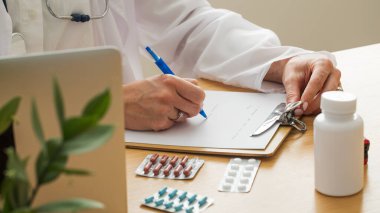 Masasında hap ve dizüstü bilgisayarla tıbbi profesyonel yazma reçetesi. Tıp kavramı.