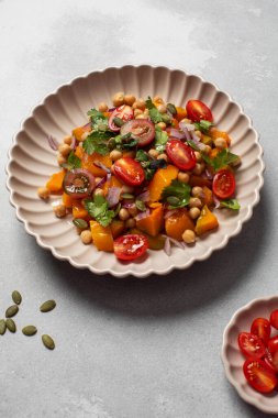 Sonbahar sıcacık bezelye ve kavrulmuş balkabağı salatası taze kiraz domatesleri ve bitkilerle birlikte. Vejetaryen ve sağlıklı salata kavramı