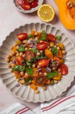 Sonbahar sıcacık bezelye ve kavrulmuş balkabağı salatası taze kiraz domatesleri ve bitkilerle birlikte. Vejetaryen ve sağlıklı salata kavramı