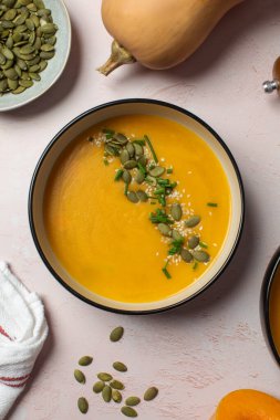 Balkabağı tohumlu kremalı kabak çorbası ve seramik kasede şifalı bitkiler. Sonbahar menüsü konsepti. Kolay vejetaryen tarifleri, ezilmiş çorba..