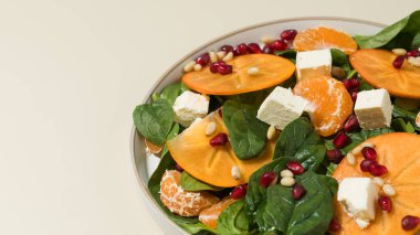 Taze hurma ve çam fıstıklı ıspanak salatası. Kış yemeği kavramı.