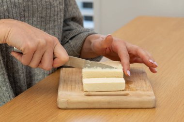 Tahtada taze peynir kesen kadın eller. Aşçılık konsepti, süt ürünleri