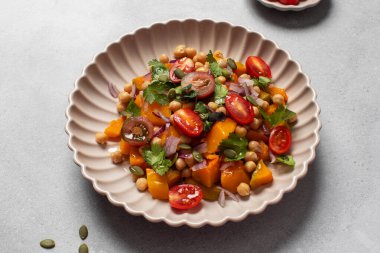 Sonbahar sıcacık bezelye ve kavrulmuş balkabağı salatası taze kiraz domatesleri ve bitkilerle birlikte. Vejetaryen ve sağlıklı salata kavramı