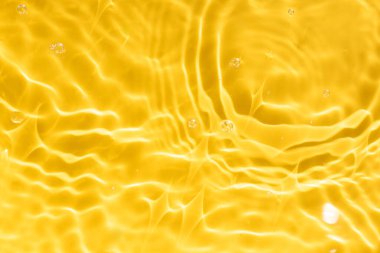 Güneş ışığı altında dalgalanan sarı suyun soyut arkaplanı. Üst manzara, düz yatış. İş için yaratıcı arka plan konsepti, kozmetik reklamcılığı. Boşluğu kopyala