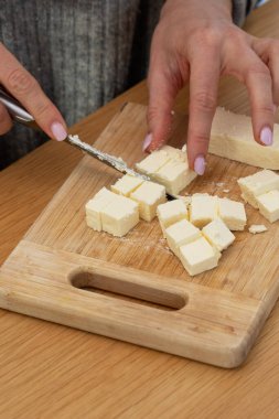 Tahtada taze peynir kesen kadın eller. Aşçılık konsepti, süt ürünleri