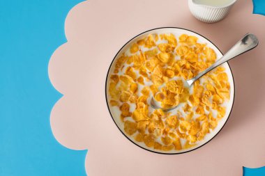 Mavi arka planda bir kasede sütlü mısır gevreği. Kahvaltı gevreği konsepti.