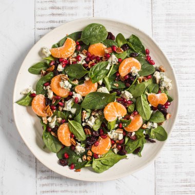 Taze ıspanak ve narlı narenciye salatası ve beyaz ahşap üzerine mavi peynir. Vejetaryenler için bayram ve Noel salatası