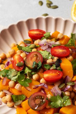 Sonbahar sıcacık bezelye ve kavrulmuş balkabağı salatası taze kiraz domatesleri ve bitkilerle birlikte. Vejetaryen ve sağlıklı salata kavramı