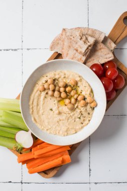 Tahta bir kasede taze humus, içinde pide, kereviz ve havuç var. Nohut yemekleri, vejetaryen yemekleri. Sağlıklı yemek.