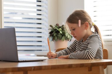 Evde çalışan, dizüstü bilgisayarın başında oturan bir çocuk. Çevrimiçi okulda okuyan tatlı bir kız. Eğitim ve e-öğrenim kavramı.