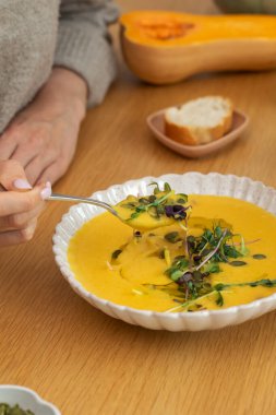 Tahta masa üzerinde mikro yeşillik ve çekirdekli kabak çorbası. Balkabağı çorbası. Vejetaryen ve sağlıklı yemek kavramı.