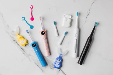 Yetişkinler ve çocuklar için ağız temizliği için farklı aksesuarlar. Aile için ultrasonik diş fırçası ve diş ipi. Ağız temizliği kavramı. 