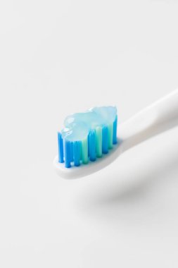 Yakından jel diş macunlu mavi tüylü beyaz bir diş fırçası. Ağız temizliği kavramı