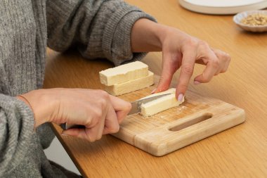 Tahtada taze peynir kesen kadın eller. Aşçılık konsepti, süt ürünleri