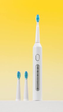 Sarı arka planda yeri doldurulabilir başlıklı ultrasonik beyaz diş fırçası. Diş sağlığı için elektrikli diş fırçası. Ağız ve diş sağlığı kavramı