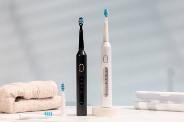 Mavi arka planda ultrasonik beyaz ve siyah diş fırçaları. Profesyonel ağız bakımı ve sağlıklı dişler kavramı 