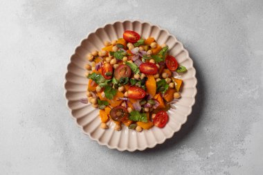 Sonbahar sıcacık bezelye ve kavrulmuş balkabağı salatası taze kiraz domatesleri ve bitkilerle birlikte. Vejetaryen ve sağlıklı salata kavramı