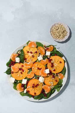 Taze hurma ve çam fıstıklı ıspanak salatası. Kış yemeği kavramı.