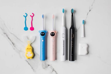 Yetişkinler ve çocuklar için ağız temizliği için farklı aksesuarlar. Aile için ultrasonik diş fırçası ve diş ipi. Ağız temizliği kavramı. 