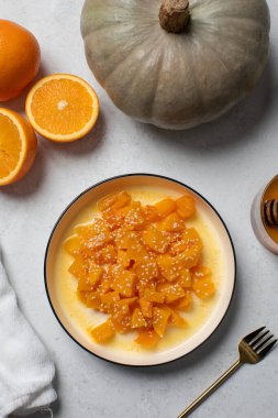 İçinde dilimlenmiş balkabağı, bal ve portakal suyu olan sağlıklı bir tatlı. Sağlıklı balkabağı yemeği konsepti.