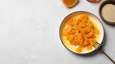 İçinde dilimlenmiş balkabağı, bal ve portakal suyu olan sağlıklı bir tatlı. Sağlıklı balkabağı yemeği kavramı. Boşluğu kopyala