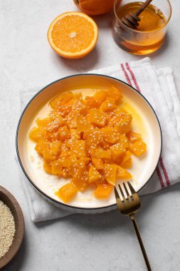 İçinde dilimlenmiş balkabağı, bal ve portakal suyu olan sağlıklı bir tatlı. Sağlıklı balkabağı yemeği konsepti.