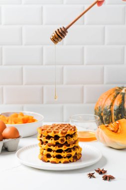 Balkabaklı waffle ve bal damlayan bir sonbahar kahvaltısı. Balkabağı tarifleri kavramı.