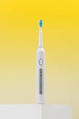 Sarı arka planda ultrasonik beyaz diş fırçası. Diş sağlığı için elektrikli diş fırçası. Ağız ve diş sağlığı kavramı. 
