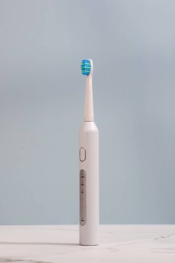 Mavi arka planda ultrasonik beyaz diş fırçası. Diş sağlığı için elektrikli diş fırçası. Ağız ve diş sağlığı kavramı.