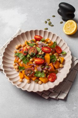 Sonbahar sıcacık bezelye ve kavrulmuş balkabağı salatası taze kiraz domatesleri ve bitkilerle birlikte. Vejetaryen ve sağlıklı salata kavramı