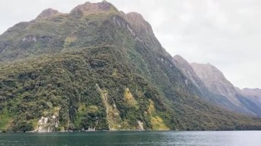 Bereketli yeşilliği olan sakin göle bakan görkemli dağ manzarası. Doğa