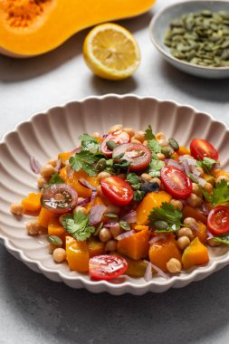 Sonbahar sıcacık bezelye ve kavrulmuş balkabağı salatası taze kiraz domatesleri ve bitkilerle birlikte. Vejetaryen ve sağlıklı salata kavramı