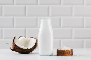 Cam şişede taze hindistan cevizi sütü ve yarım hindistan cevizi. Vejetaryen sağlıklı süt kavramı