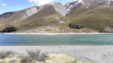 Flying over a clear lake surrounded by hills in New Zealand. The concept of travel and nature.
