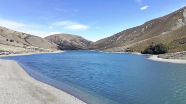 Flying over a clear lake surrounded by hills in New Zealand. The concept of travel and nature.