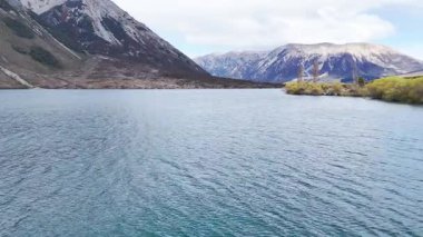 Majestic mountain lake rippling under cloudy sky amidst rocky scenery. New Zealand. Concept of travel and nature