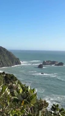 Scenic coastal landscape with waves crashing against rocky shoreline on a clear day. West Coast, New Zealand. Concept of travel 