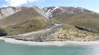 Aerial view of serene mountain lake with snowdusted peaks and quiet shoreline. Concept of travel and nature