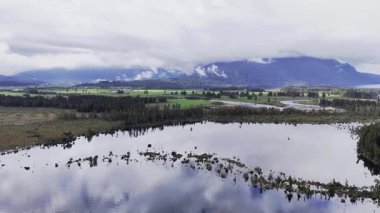 An aerial view of a serene lake and lush forest landscape with reflecting water. A landscape of untouched wilderness.