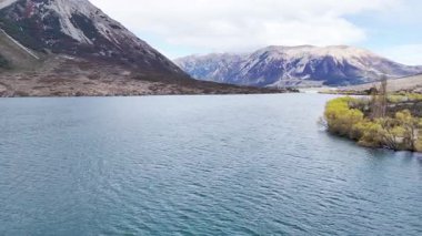 Majestic mountain lake rippling under cloudy sky amidst rocky scenery. New Zealand. Concept of travel and nature