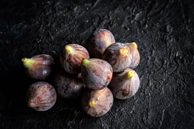 Siyah Rimmed Bordissot çeşitliliğinin koyu arkaplanda taze incirleri.